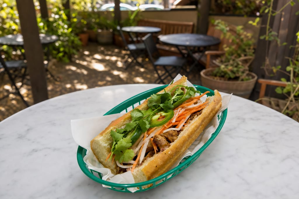 Five spice chicken banh mi: browned chicken, pickled carrot and daikon, jalapeño and cilantro in a green basket on the patio