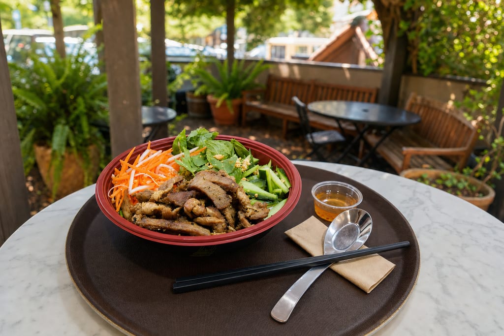 Chicken fresh bowl: grilled chicken, pickled carrot and daikon, basil, cucumber and peanuts in a red bowl on a brown tray